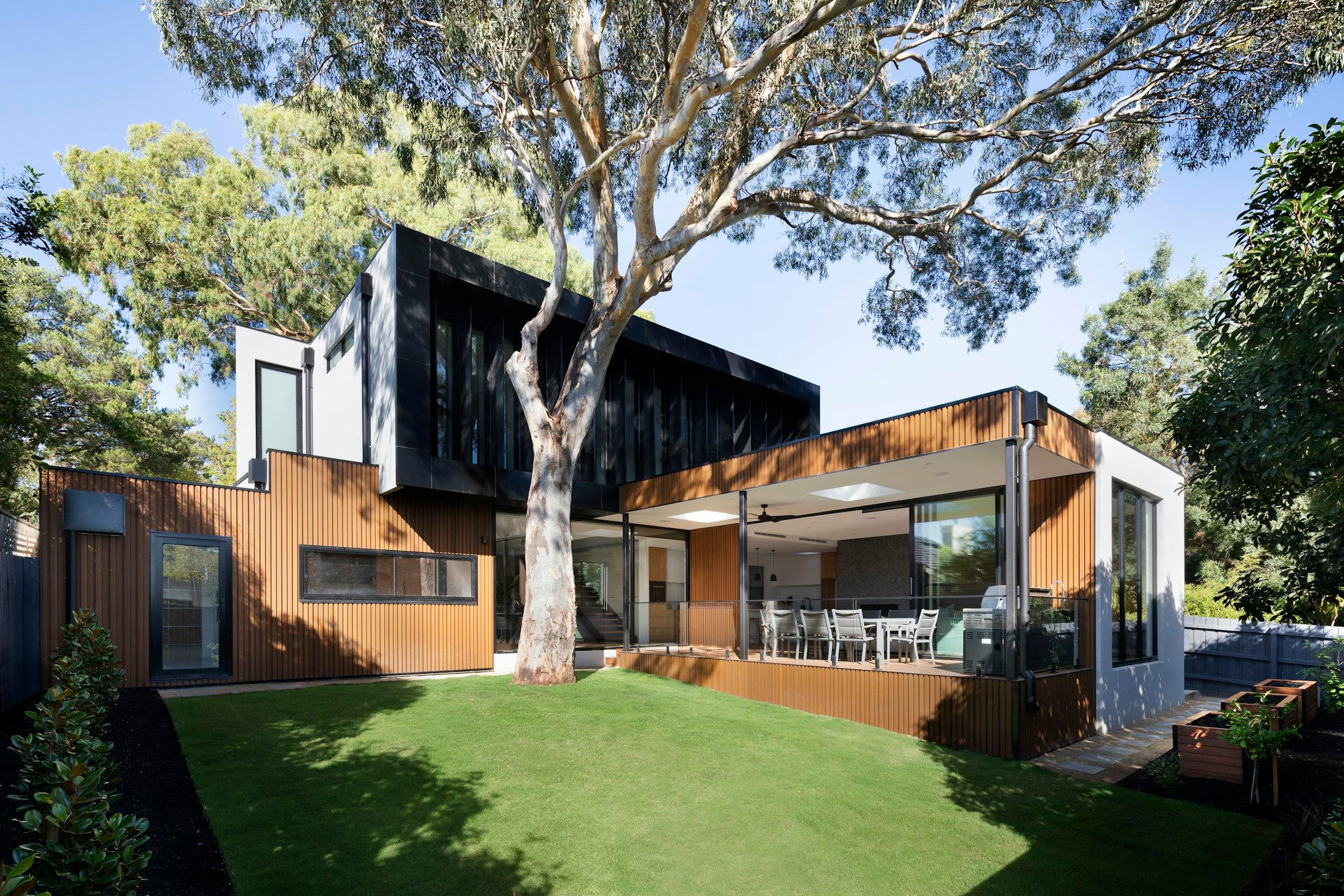 Modern timber and black-clad residence set beneath mature trees
