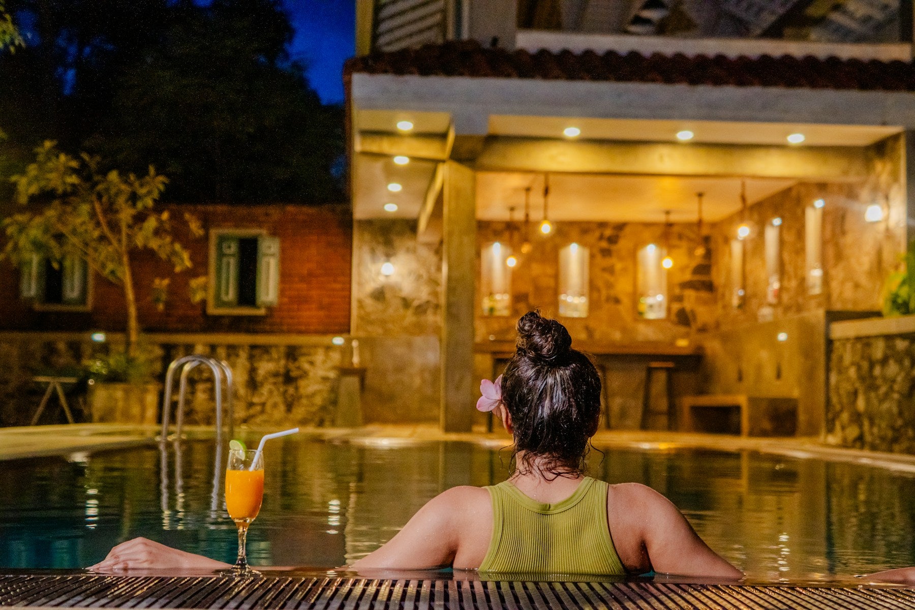A guest relaxing in a warmly lit pool at night